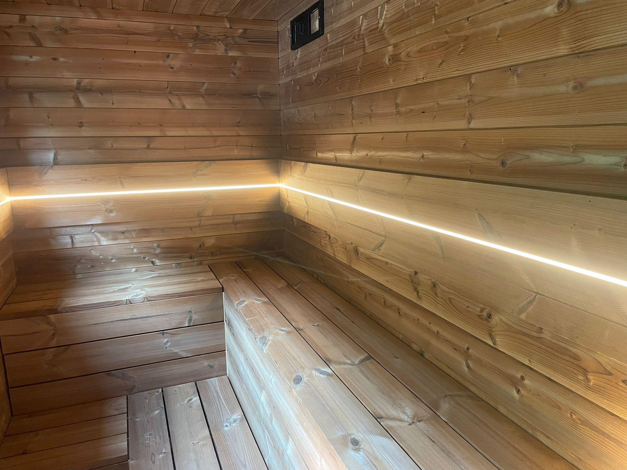 Inside the KUUMA sauna with timber benches and warm lighting